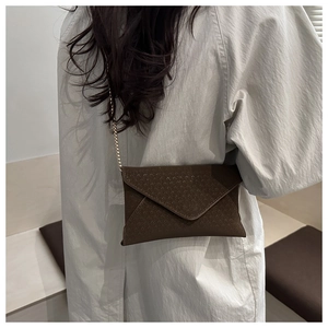 Détail du sac bandoulière enveloppe marron foncé gaufré avec chaîne dorée sur mannequin