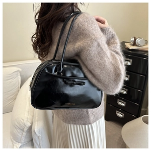 Détail d'un sac sous les aisselles noir brillant avec nœud en cuir et lettrage doré