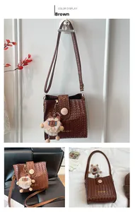 Detail of brown woven leather bucket bag with wooden buckle and bear charm