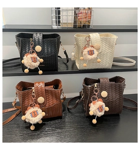 Detail of four woven bucket bags in black, beige, tan, and dark brown with cute charms