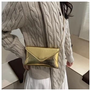Detail of gold envelope crossbody bag with fine ripple texture and chain strap
