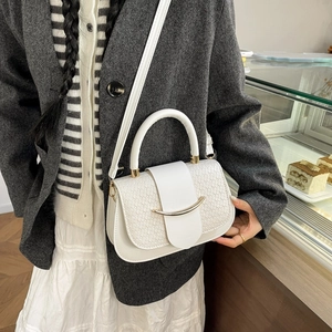 Gros plan d'un sac blanc à texture tissée avec décor métallique doré et bandoulière