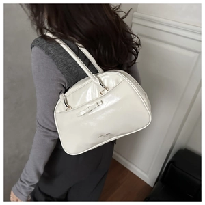 Détail du sac polochon blanc en cuir brillant avec un nœud et une impression de logo