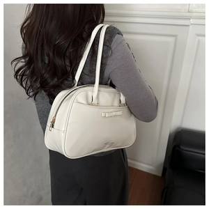 Close-up of beige PU leather shoulder bag with bow detail and golden zipper hardware