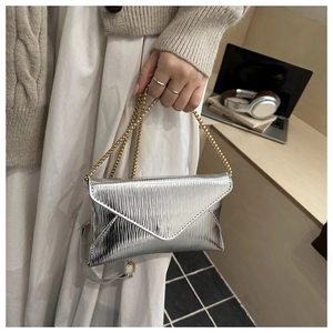 Detail of silver envelope bag featuring vertical texture and dual metallic chain straps