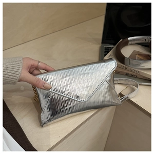 Detail of silver envelope bag with water ripple texture and dual chain shoulder straps