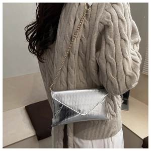 Macro shot of silver envelope crossbody bag with wave texture leather and golden chain