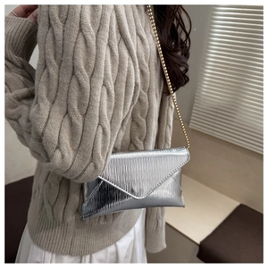 Detailed view of silver metallic pleated envelope bag with elegant gold chain strap