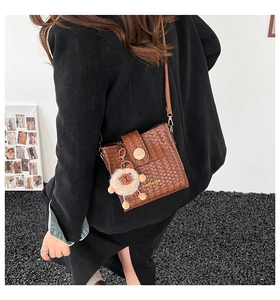 Detail of brown woven PU leather bucket bag with wooden buckle and plush lion charm