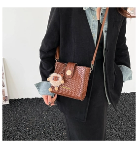 Brown woven crossbody bag with cute lion charm detail shown on a fashion model