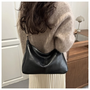 Schwarze Retro-Hobo-Tasche aus Kunstleder, getragen in einem minimalistischen Interieur