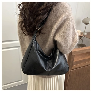 Side view of model wearing a black crescent underarm bag with vintage oil wax leather texture