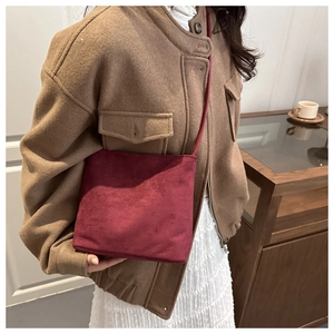 Macro detail of wine red matte suede shoulder bag with Fashion and Classic embossed text