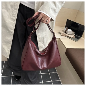 Detail view of burgundy hobo bag with wide strap and red lining in lifestyle scene