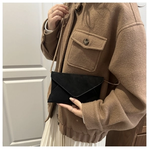 Detail of black suede envelope chain bag worn with a casual vintage outfit