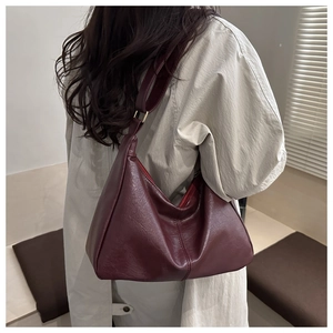 Detail of burgundy hobo shoulder bag with glossy oil wax texture and adjustable strap