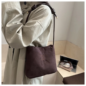Detail of dark brown suede shoulder bag with knotted strap and minimalist logo print