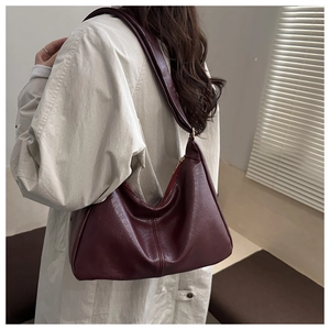 Detailed side view of a deep red shoulder bag showing soft pleats and metal zipper
