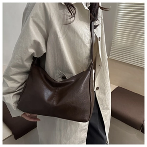 Detail of dark brown leather hobo bag with vertical stitching and smooth zipper closure