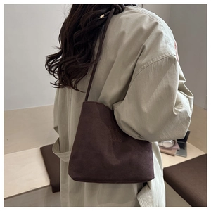 Detail of the suede texture and fashion and classic embossed text on the coffee bucket bag