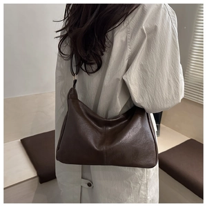 Detail view of large coffee PU leather tote bag worn as a stylish underarm shoulder bag