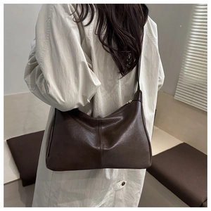 Detail of dark brown leather hobo bag with vertical stitching and wide shoulder strap