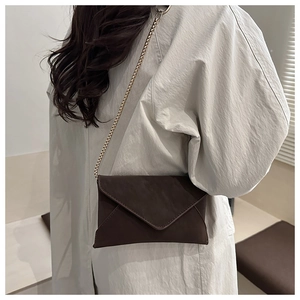 Detailed view of deep brown frosted leather texture and gold chain on crossbody bag