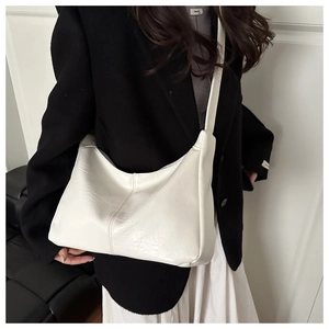Detailed view of white minimalist leather shoulder bag with smooth crescent silhouette