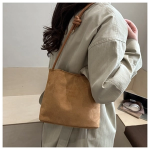 Close-up of brown suede bucket bag with fashion and classic embossed text detail