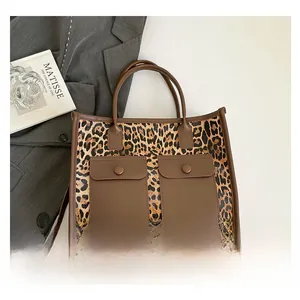 Detail of leopard print tote bag with brown leather pockets and shoulder strap details