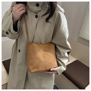 Detail of caramel suede bucket bag featuring fashion and classic embossed lettering