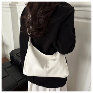 Detail of white pleated shoulder bag with wide strap and metal rings on female model