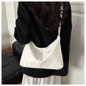 Rear view of model wearing a minimalist white crescent shoulder bag in matte leather