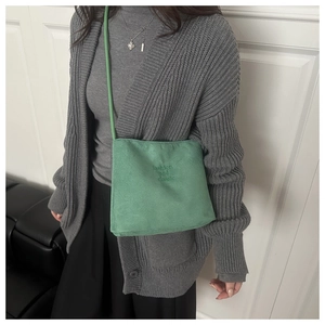 Detail of green suede bucket bag with fashion and classic embossed text on model