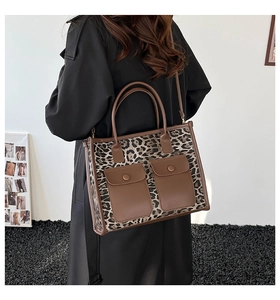 Detail of leopard print tote bag with brown leather accents and adjustable shoulder strap