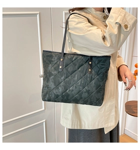 Detailed view of large quilted tote bag in dark grey camouflage with leather straps
