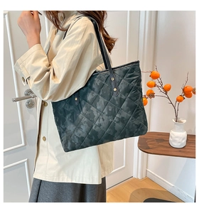 Detailed side view of dark green quilted tote bag with camo pattern on shoulder