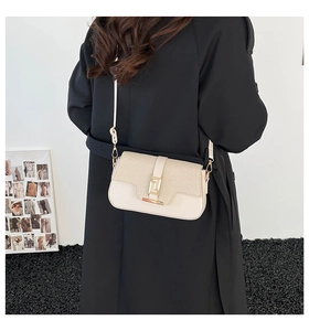 Detail of cream leather and fabric saddle bag with gold metal buckle on a model