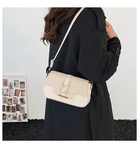 Detail of minimalist cream saddle bag with gold buckle on a model in side view