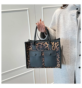 Close-up of leopard print tote bag featuring black leather front pockets and slim handles