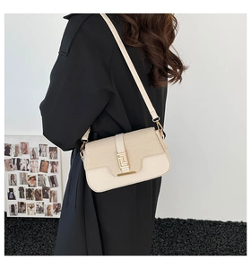 Detail of beige saddle bag showing mixed leather texture and gold geometric buckle