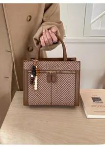 Detail of vintage brown tote bag with herringbone texture and wood bead pendant charm