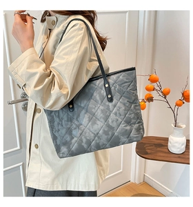 Close-up of a quilted dark grey tote bag with camouflage print and gold metal buckle
