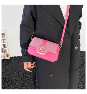 Detail of pink patchwork crossbody bag with gold metal buckle on a black coat