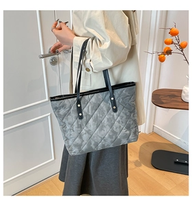 Detail of grey quilted tote bag with diamond pattern and slim black shoulder straps