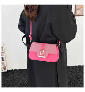 Detail view of pink crossbody bag with woven flap and gold buckle on black coat