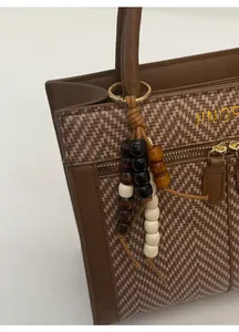 Close-up of vintage brown woven tote bag featuring ethnic beaded tassel and gold zipper