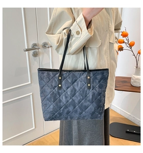 Detail of blue camouflage quilted tote bag featuring golden rivets and slim shoulder straps
