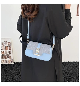 Detailed view of a light blue crossbody bag worn by a model in a black trench coat