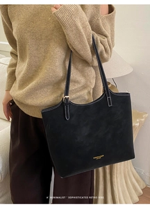 Détail du sac cabas noir avec surpiqûres blanches et logo de mode doré élégant